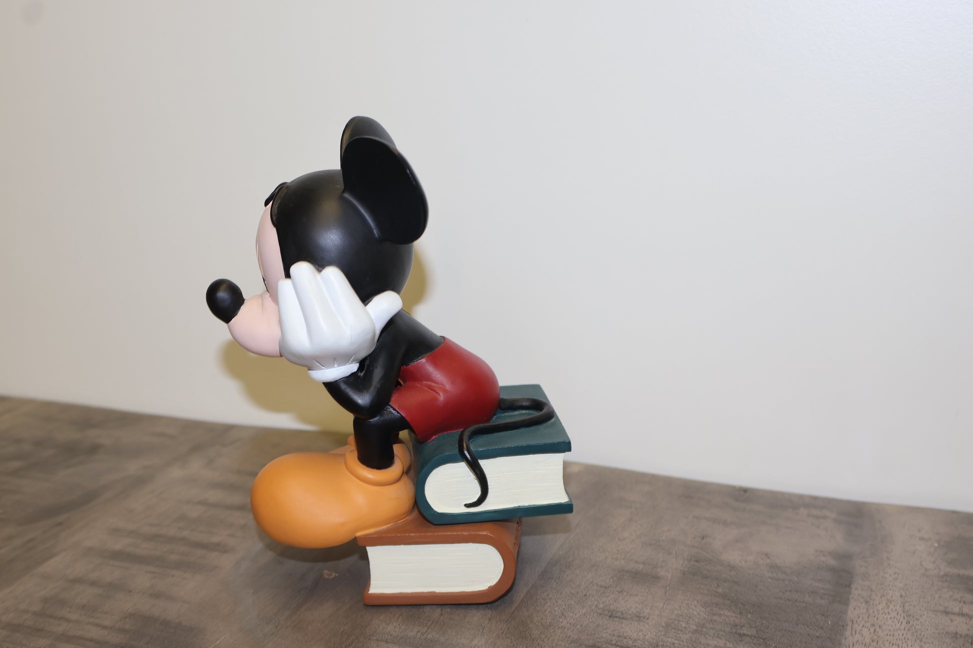 Iconisch beeld van Mickey zittend op een stapel boeken.